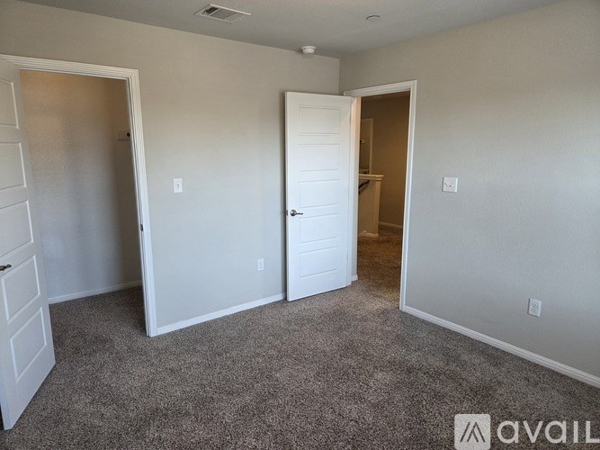 A room with carpeted floor and two doors, one of which is open.