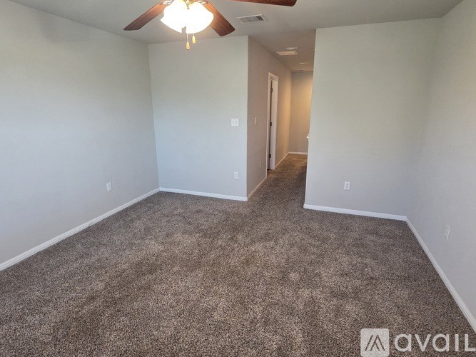A room with a carpeted floor and a ceiling fan.