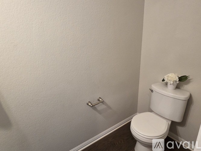 A white toilet with a white flower on top of a white tank.