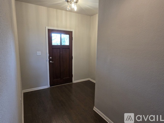 A room with a wooden door and a chandelier.