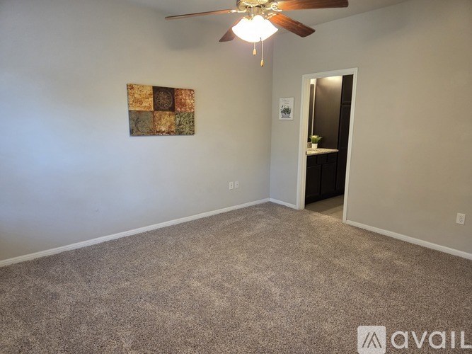 A room with a ceiling fan and a wall hanging picture.