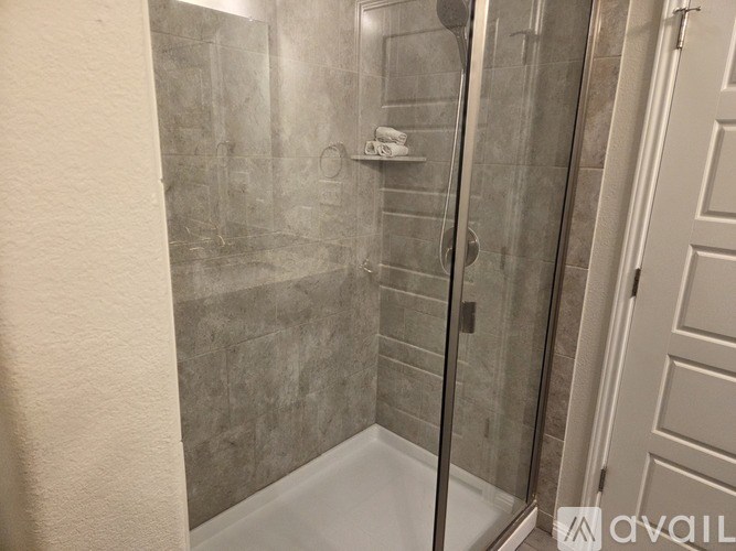 A shower with a glass door and a tiled wall.