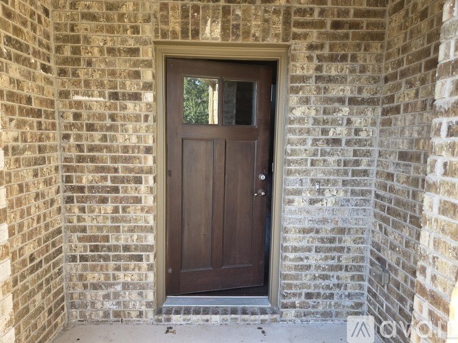 A brown door is set in a brick wall.