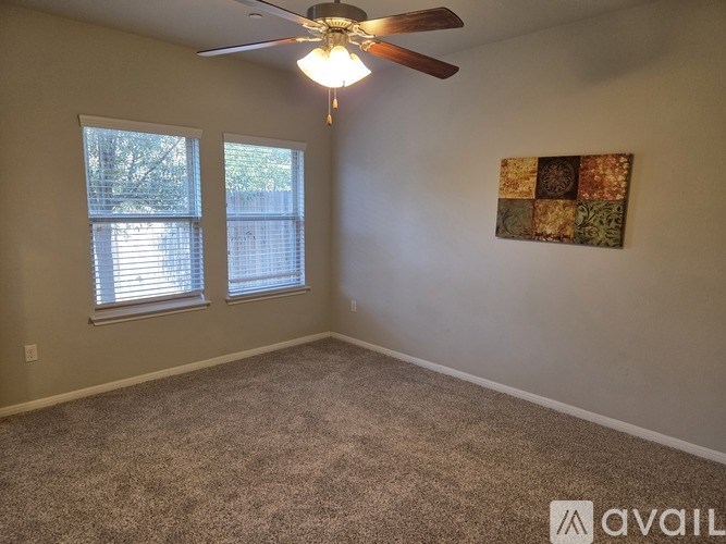 A room with a ceiling fan and a painting on the wall.