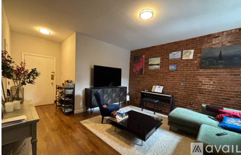A living room with a brick wall and a grey couch.