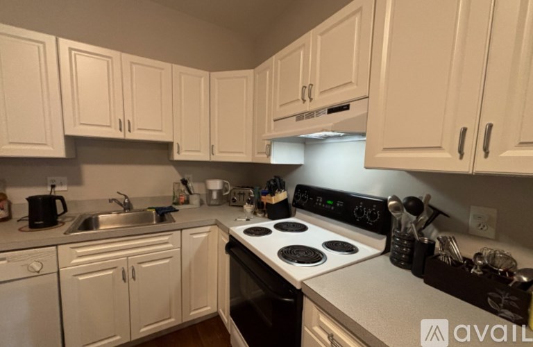 A kitchen with white cabinets and a stove top oven.