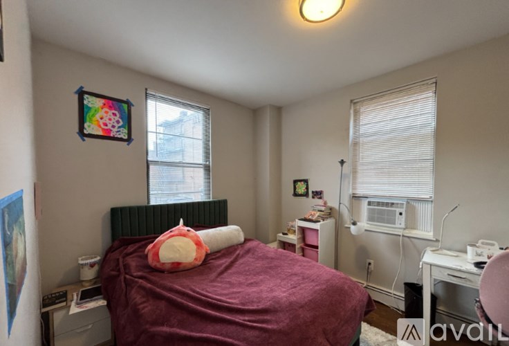 A bedroom with a bed, desk, and window.
