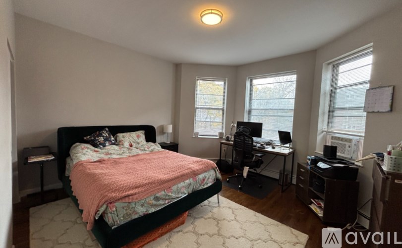 A bedroom with a bed, desk, and chair.