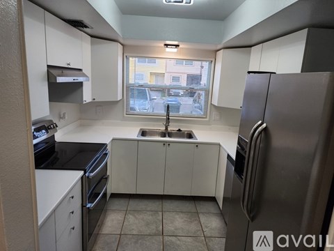 A kitchen with white cabinets and a black refrigerator.