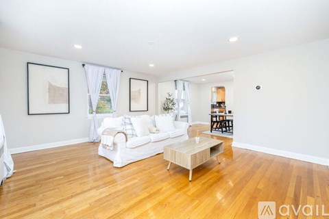 A living room with a white couch and wooden floors.