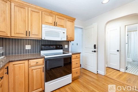 A kitchen with wooden cabinets and a white microwave above the oven.