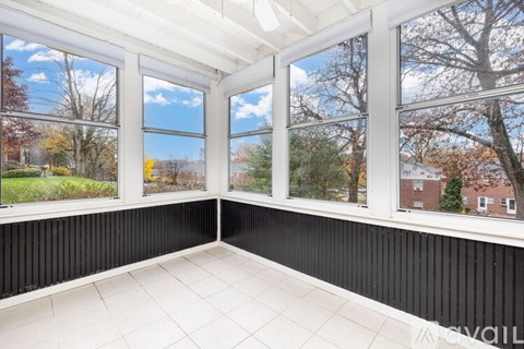A sunny day in a room with large windows and a view of trees and houses outside.