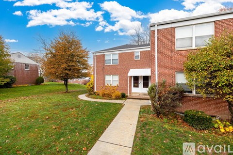A brick building with a white door and a small tree in front.