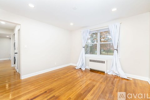 A room with wooden floors and a window with white curtains.