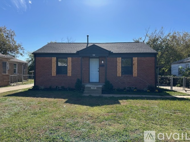 A small brick house with a white door and windows is for sale.