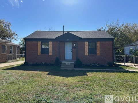A small brick house with a white door and windows is for sale.