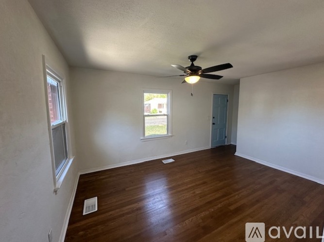 A room with a ceiling fan and wooden flooring.