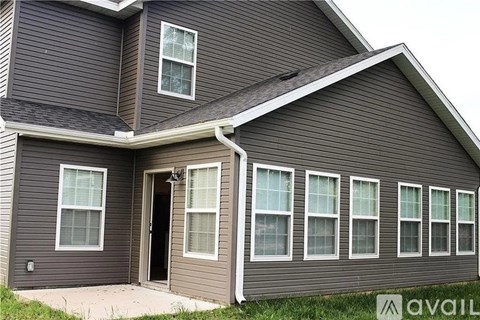 A house with a brown siding and a black door is available for rent.
