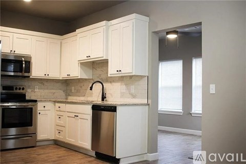 A kitchen with white cabinets and a marble backsplash.