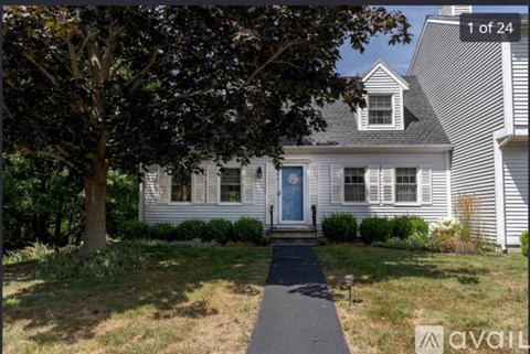 A white house with a blue door and a tree in front.