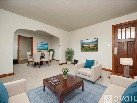 A living room with a couch, chairs, a coffee table, and a painting on the wall.