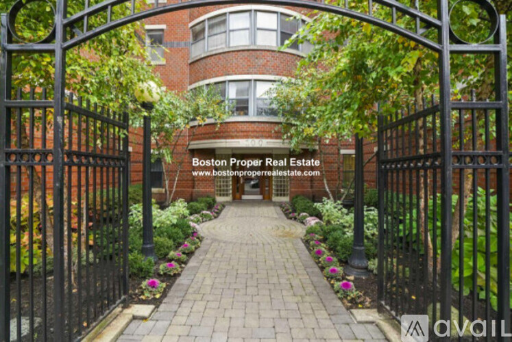 A gated entrance to a brick building with a sign that says Boston Proper Real Estate.