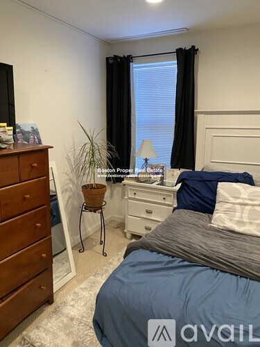 A bedroom with a bed, dresser, and window with black curtains.