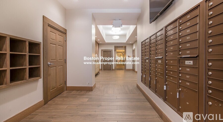 A hallway with wooden floors and a row of mailboxes on the right.
