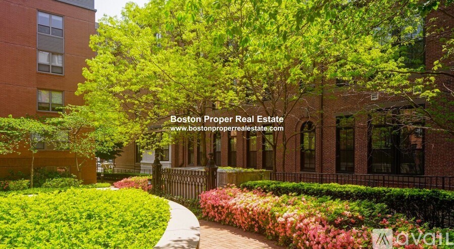 A well-maintained garden in front of a brick building with the text "Boston Proper Real Estate" and a website address.