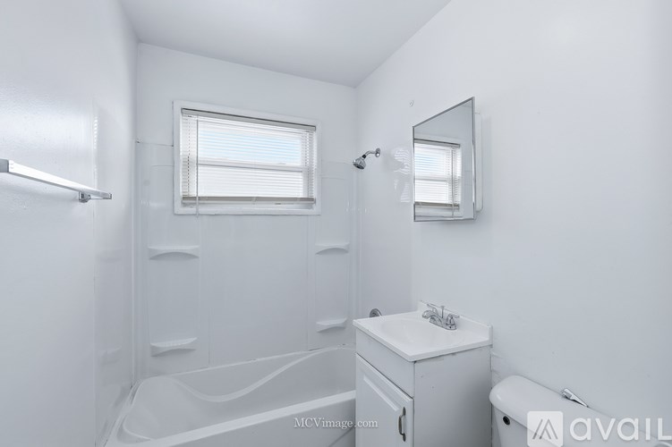 A white bathroom with a tub, sink, and mirror.