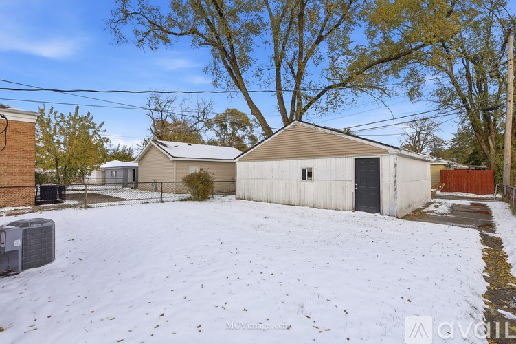 A snow-covered yard with a white garage and a brown roof.