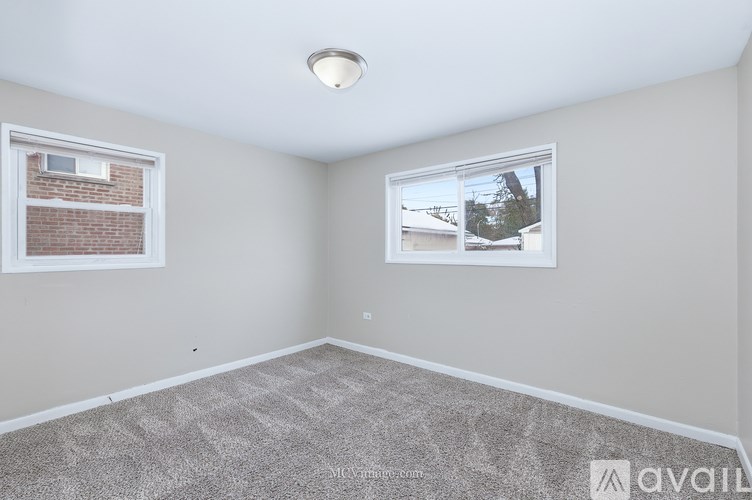 A room with a carpeted floor and a window showing a view of a house.