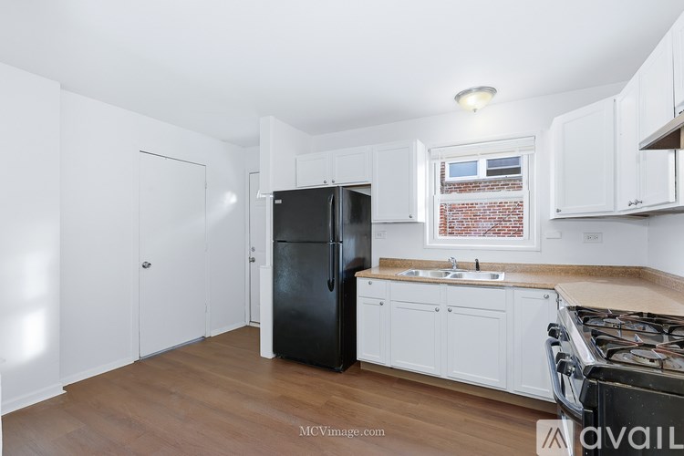 A kitchen with white cabinets and a black refrigerator.
