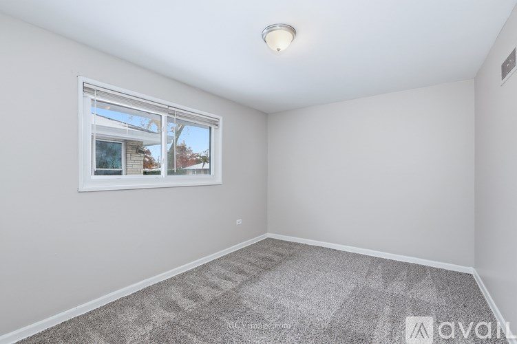 A room with a window and a carpeted floor.
