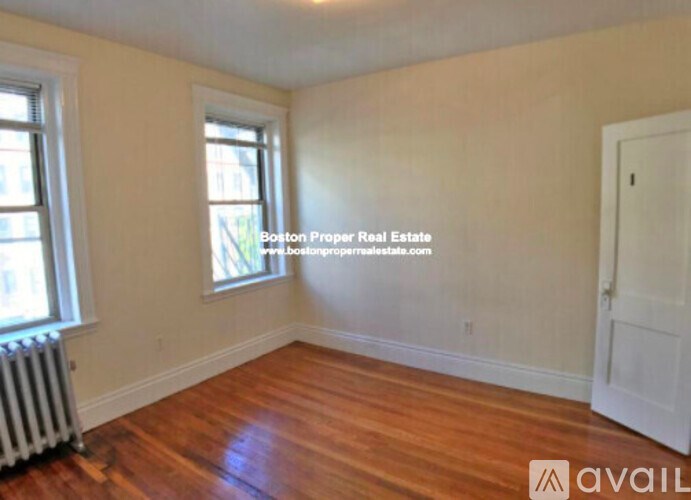 A room with wooden floors and a white door is available for rent.