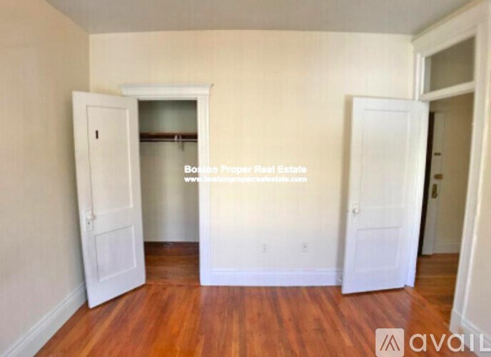 A room with wooden floors and two white doors, one of which is open.