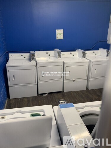 A row of white washing machines in a blue room.
