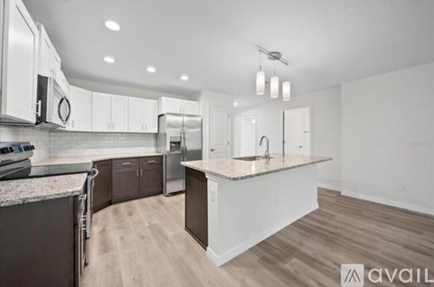 A modern kitchen with dark brown cabinets and a granite countertop.