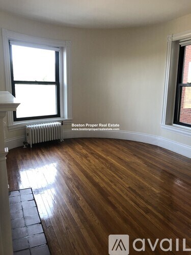 A room with wooden floors and two windows.