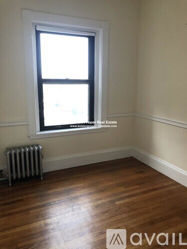 A room with wooden floors and a window with a view of the city.