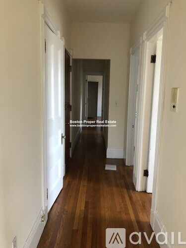 A long hallway with wood floors and white walls.