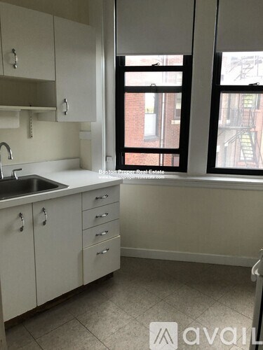A kitchen with white cabinets and a window.