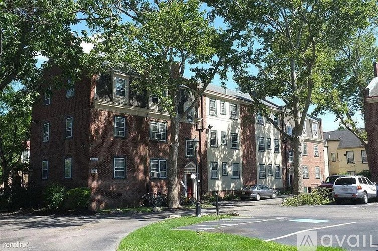A street view of a residential area with apartment buildings and parked cars.