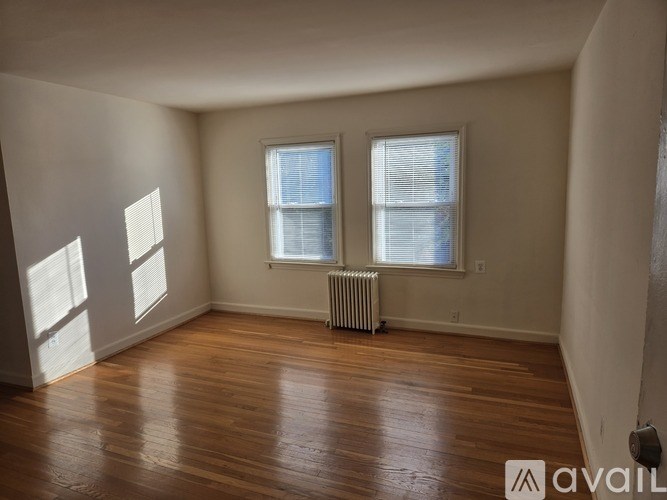 A room with wooden floors and two windows.