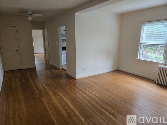 A room with wooden floors and a window with blinds.