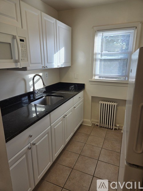 A kitchen with white cabinets and black countertops.