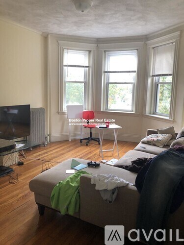 A living room with a couch, a television, and a window.