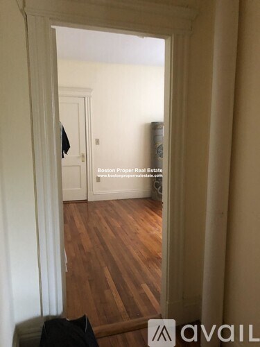 A room with wooden floors and a door in the background.