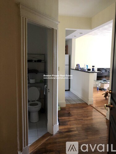 A bathroom with a toilet and a doorway leading to another room.