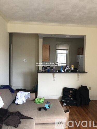 A living room with a grey couch and a black backpack on the floor.